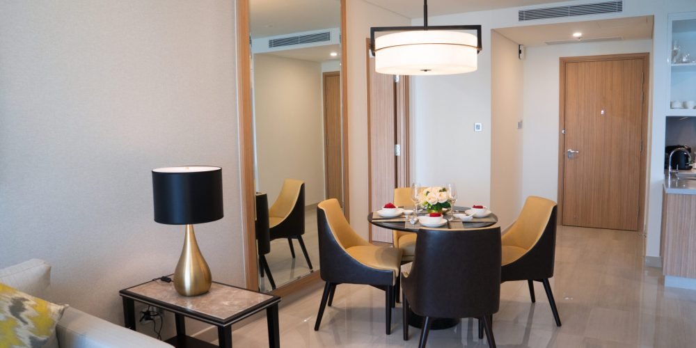 Dining area of comfortable studio flat or hotel room. Set dining table prepared for dinner with Asian cuisine. City apartment and interior concept